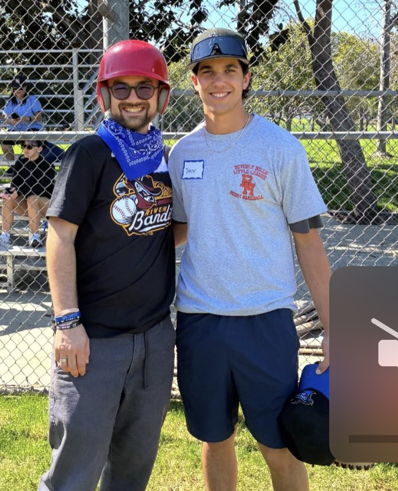 A River Bandits player in a batting helmet with his buddy at the backstop