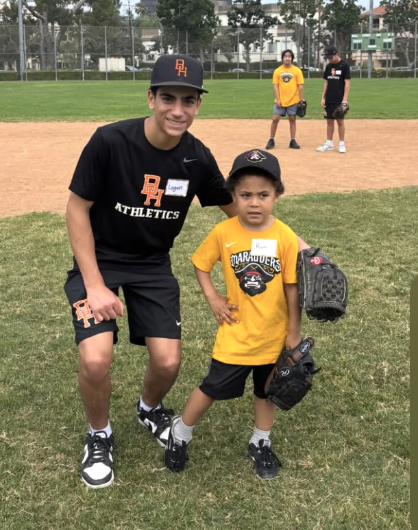 A teen volunteer in an Athletics shirt with a Marauders player wearing a glove